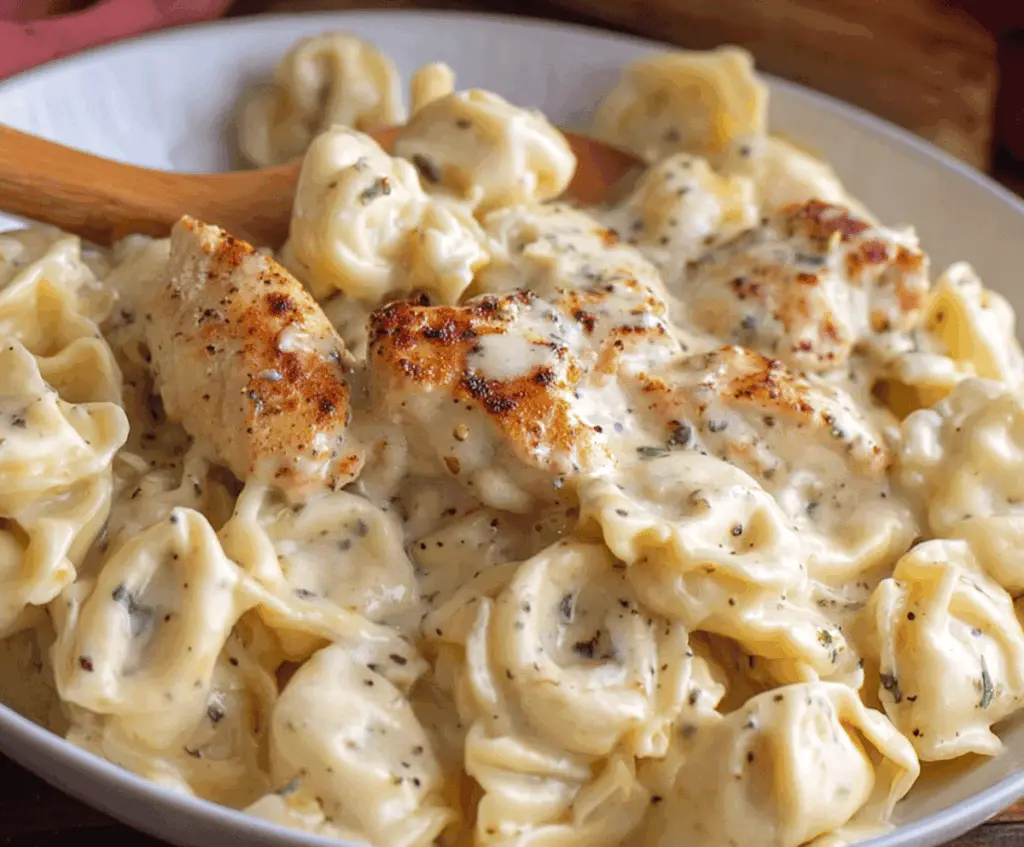 Creamy Garlic Parmesan Chicken Tortellini dish topped with fresh herbs and grated cheese, served on a white plate.