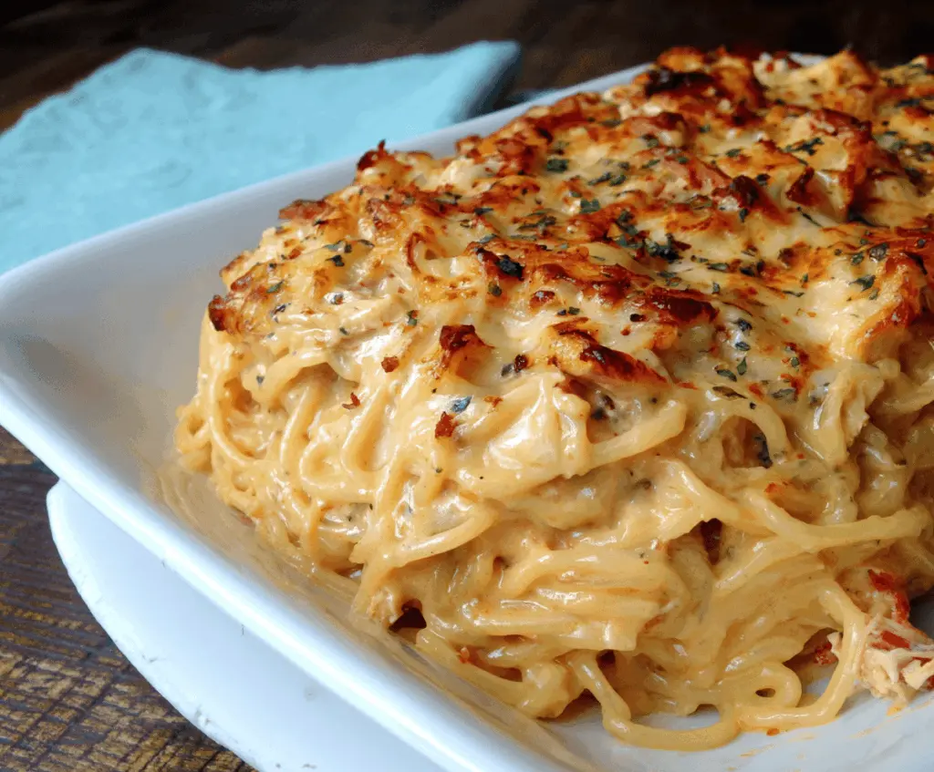Creamy spicy Southern chicken spaghetti casserole topped with melted cheese and fresh herbs, served in a baking dish