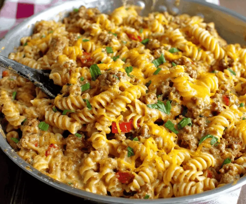 Creamy cheesy ground turkey pasta served in a bowl, featuring melted cheese, ground turkey, and pasta garnished with herbs, perfect for a comforting and easy meal.