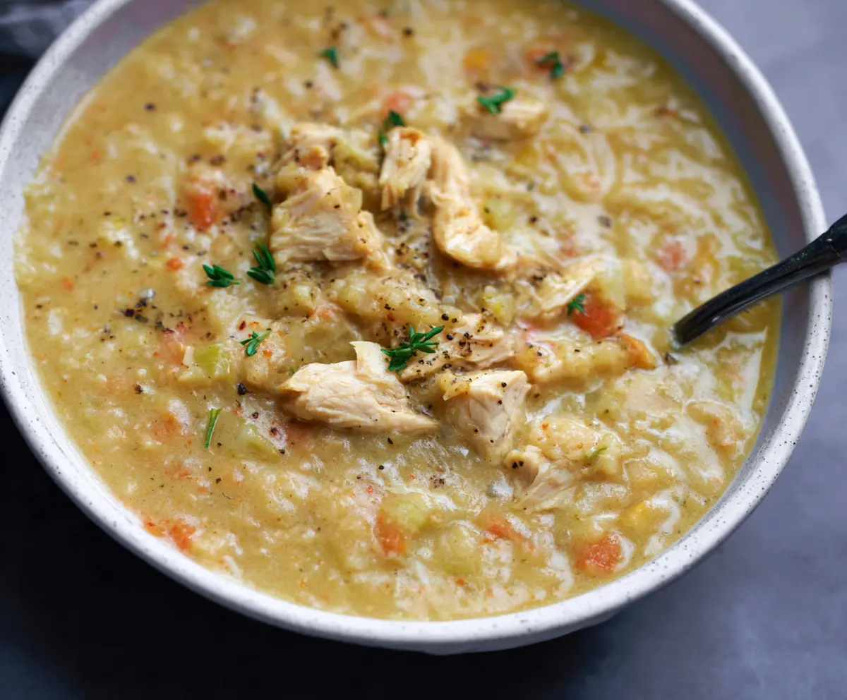 Bowl of creamy cauliflower chicken soup garnished with herbs, prepared in 30 minutes.