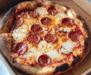 Homemade sourdough pizza dough ready for baking on a wooden surface.